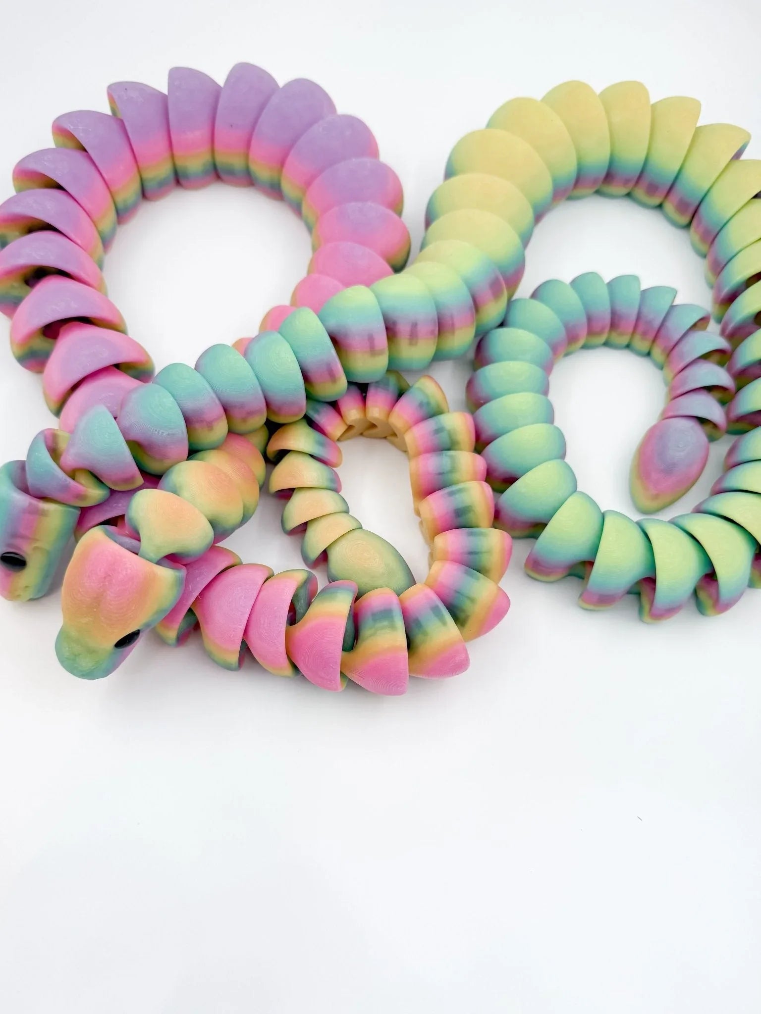 3D printed rainbow articulated snake glow-in-the-dark fidget toy on white background