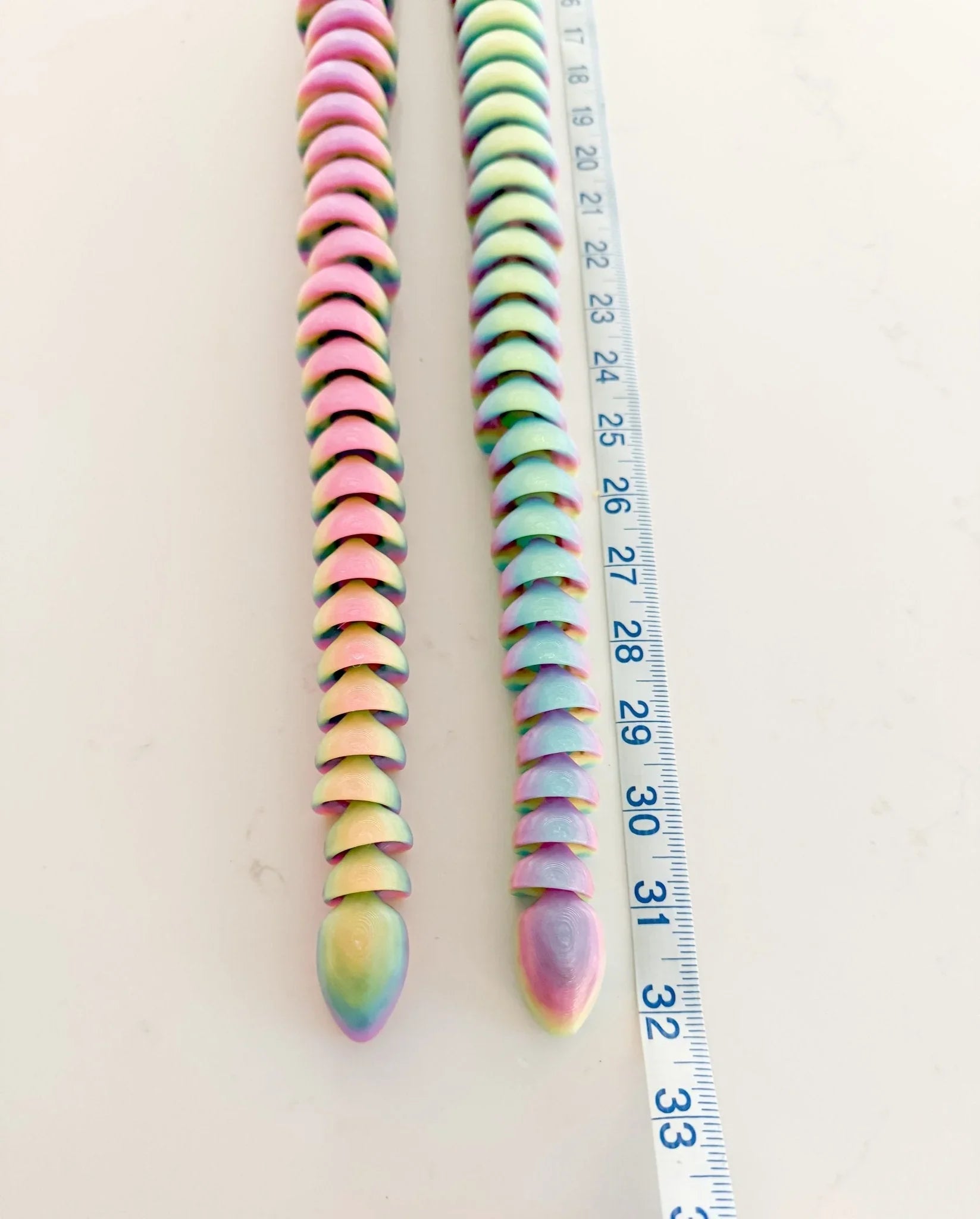 32-inch articulated rainbow snake 3D printed glow-in-the-dark fidget toy next to ruler