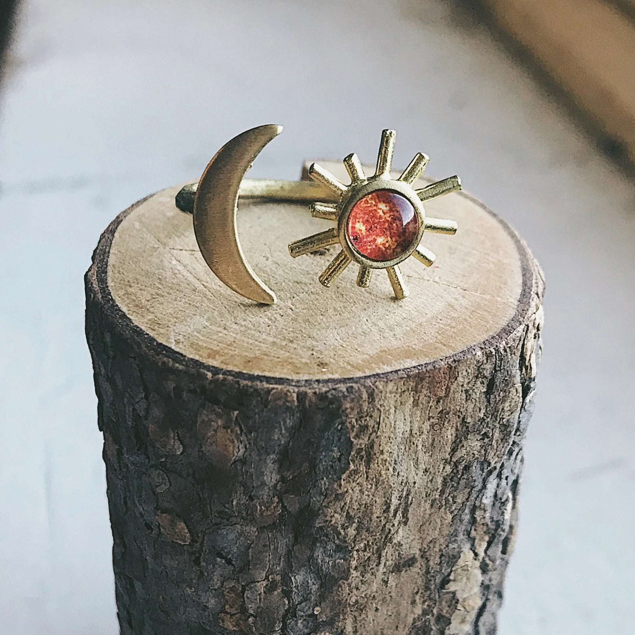 Gold sun and crescent moon ring displayed on a natural wood stump