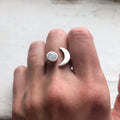 Hand wearing a silver moon and gemstone ring, cosmic jewelry at Qu!rk Boutique