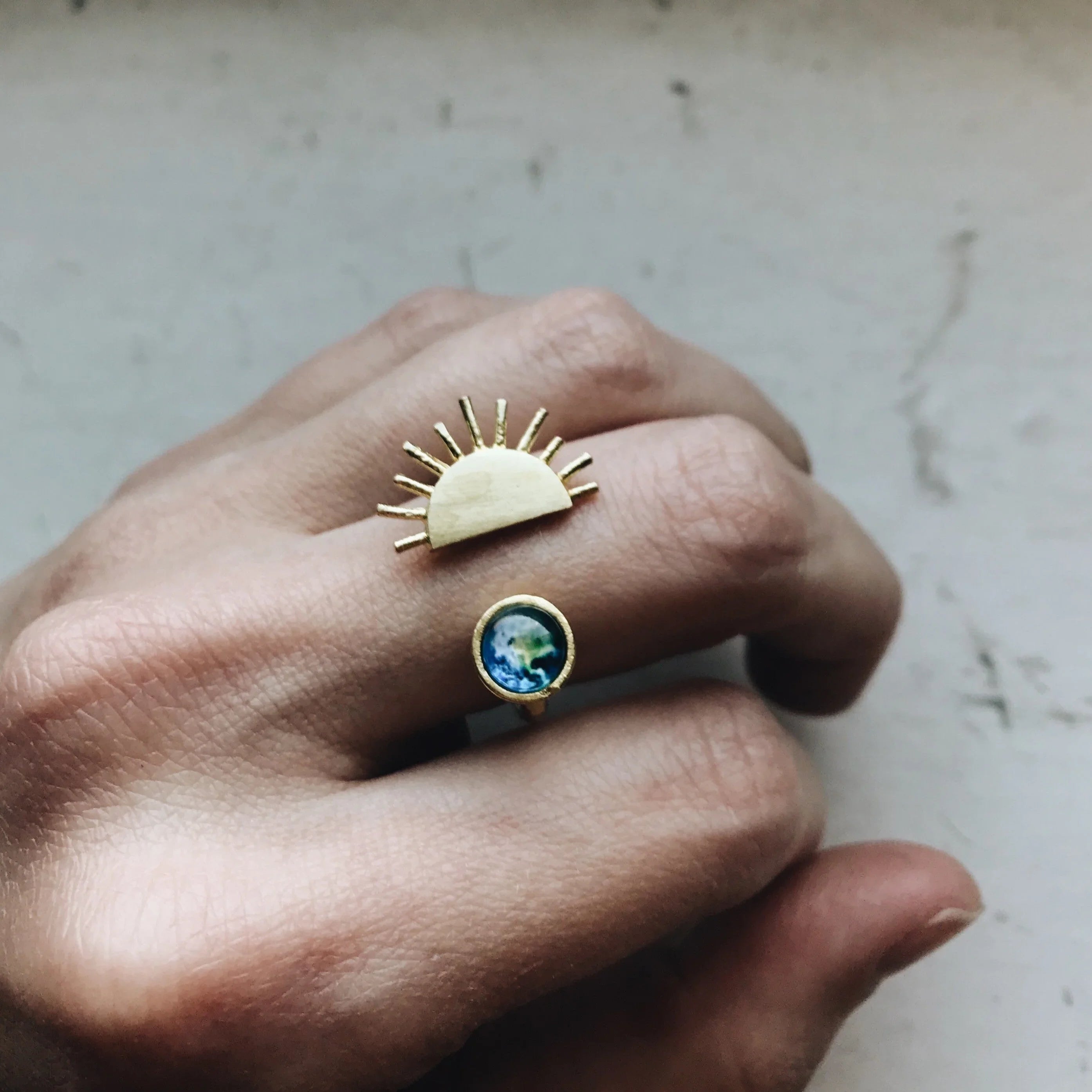 Hand wearing Qu!rk Boutique gold sun and Earth art ring, sustainable cosmic jewelry