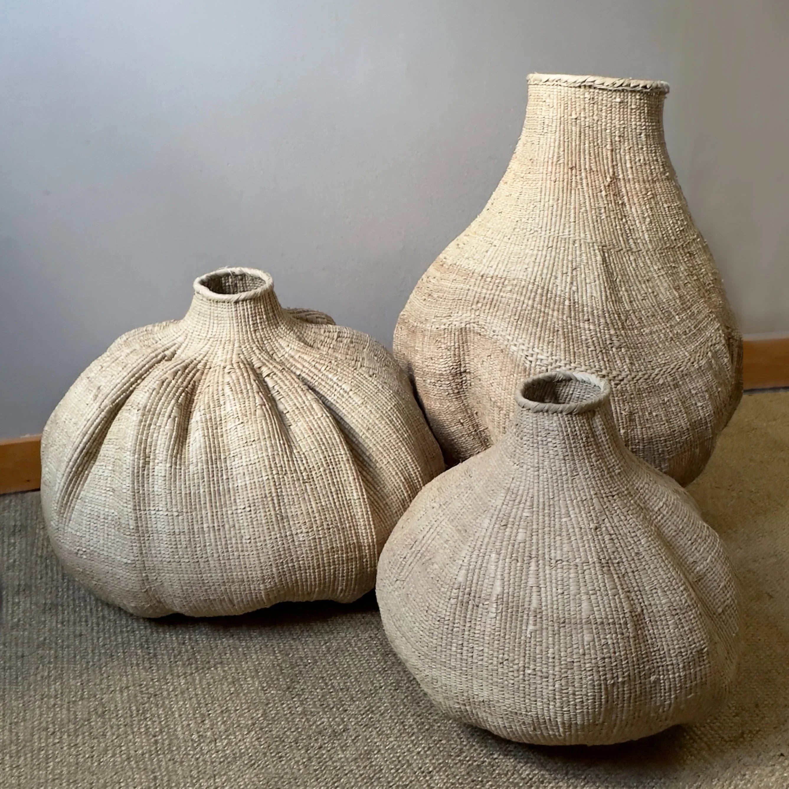 Set of three large, handwoven natural fiber baskets on carpet, Qu!rk Boutique sustainable decor