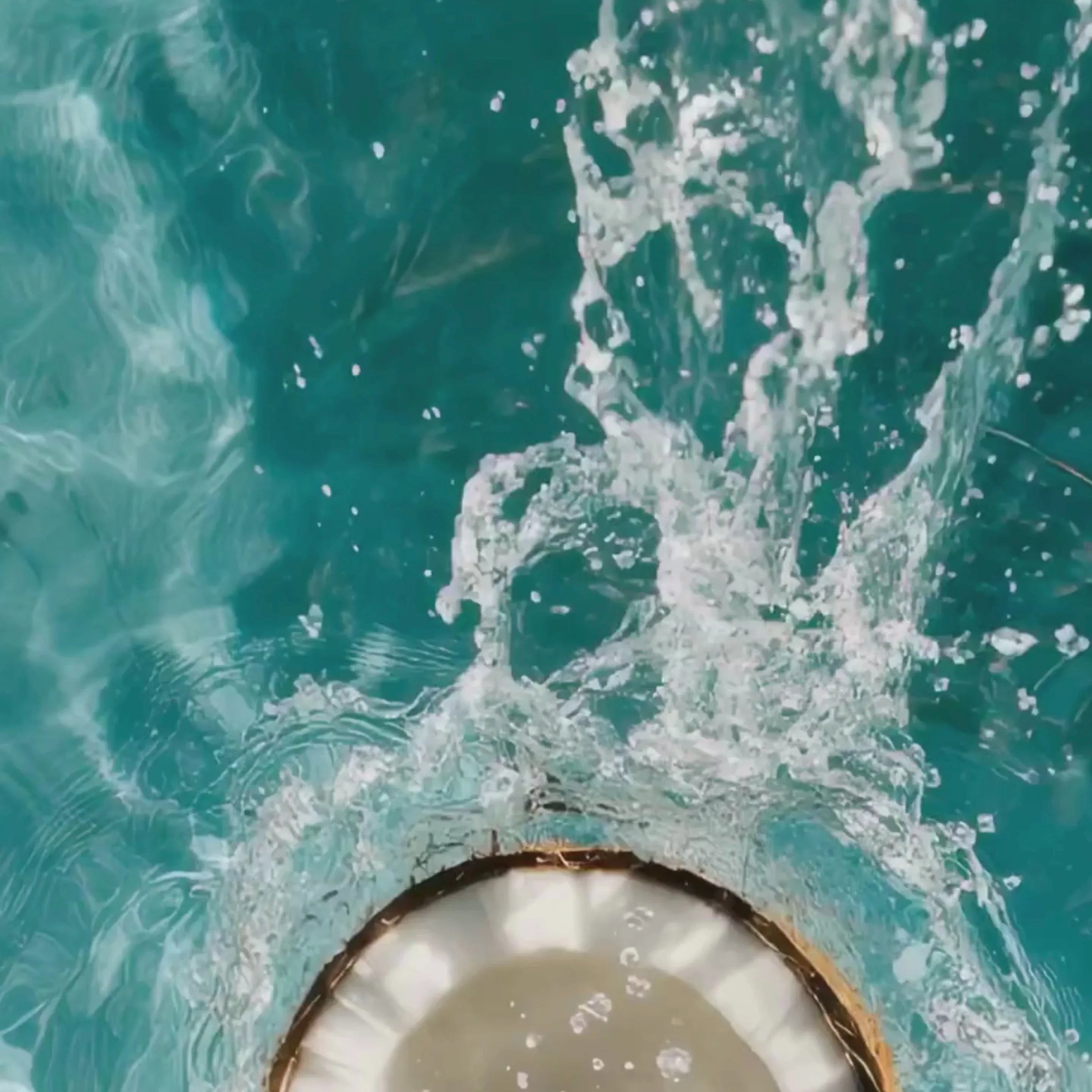 Splashing water over a round drain in clear turquoise pool, cosmic boutique aesthetic