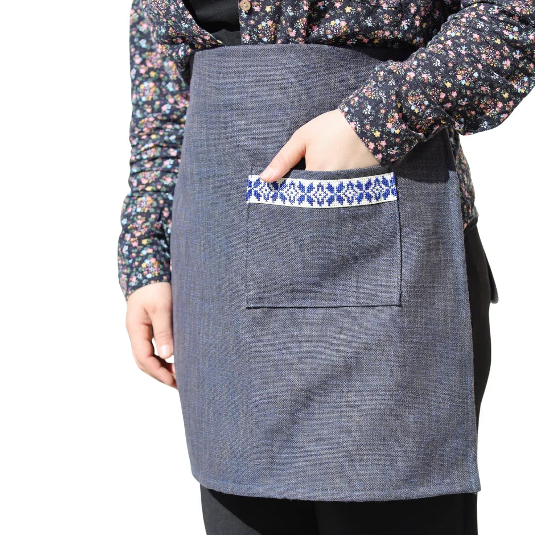 Handmade denim half apron with embroidered front pocket, modeled with a floral blouse.