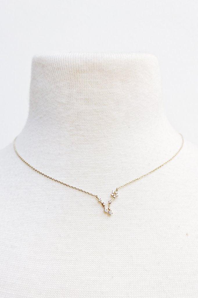 Delicate gold constellation necklace with small crystals on white fabric display bust