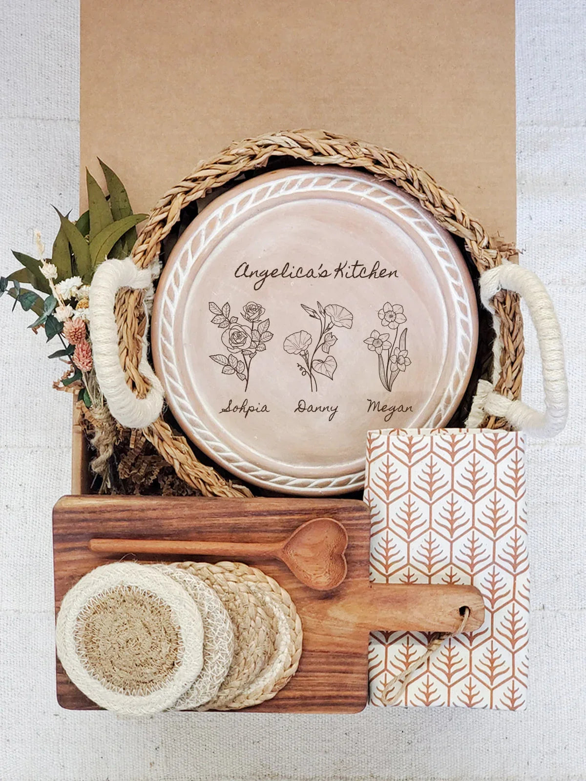 Rustic kitchen gift set with personalized ceramic plate, woven basket, wooden spoon, coasters, and patterned napkin