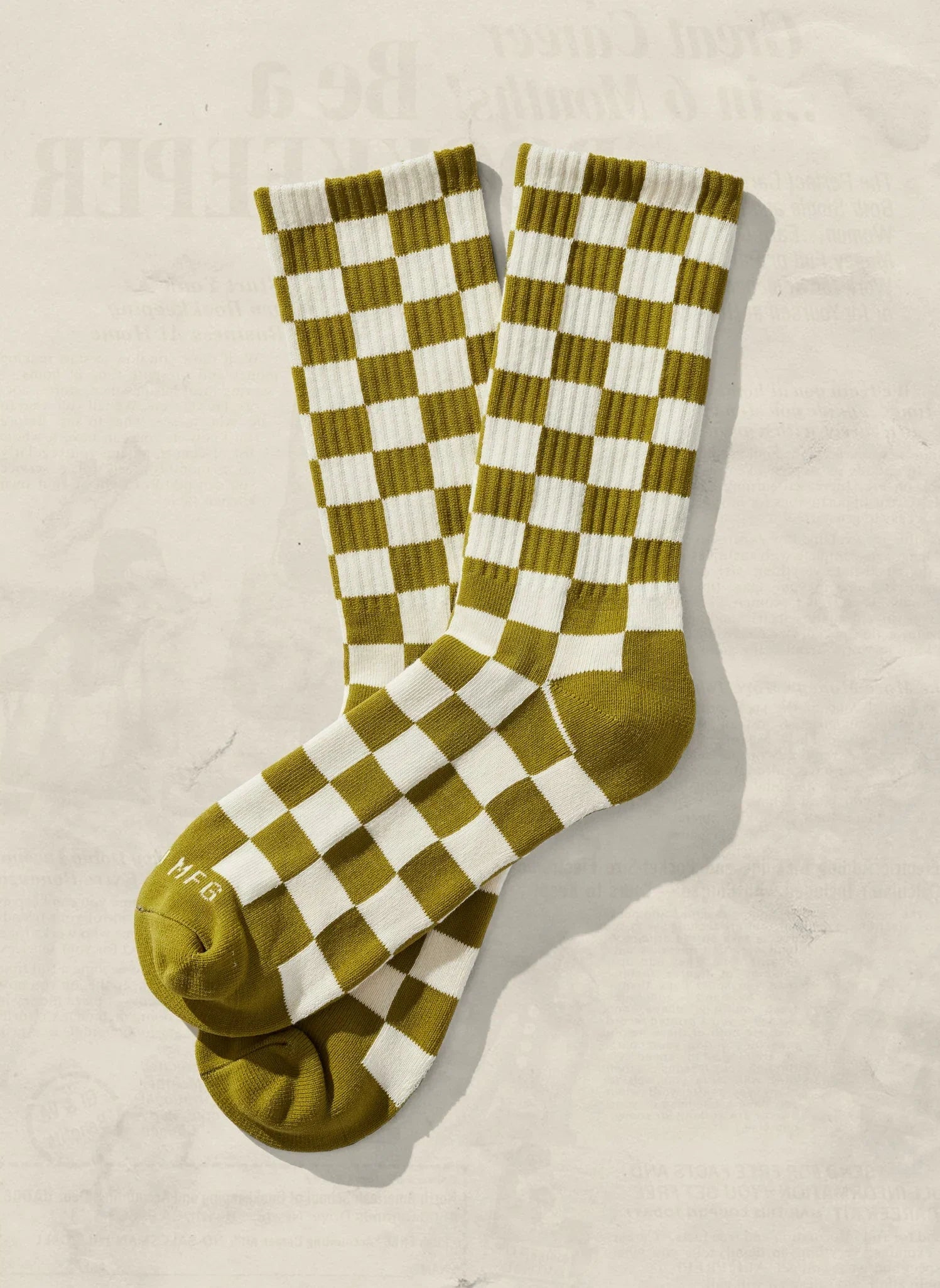 Olive green and white checkered socks on neutral background, Qu!rk Boutique artist-designed gift