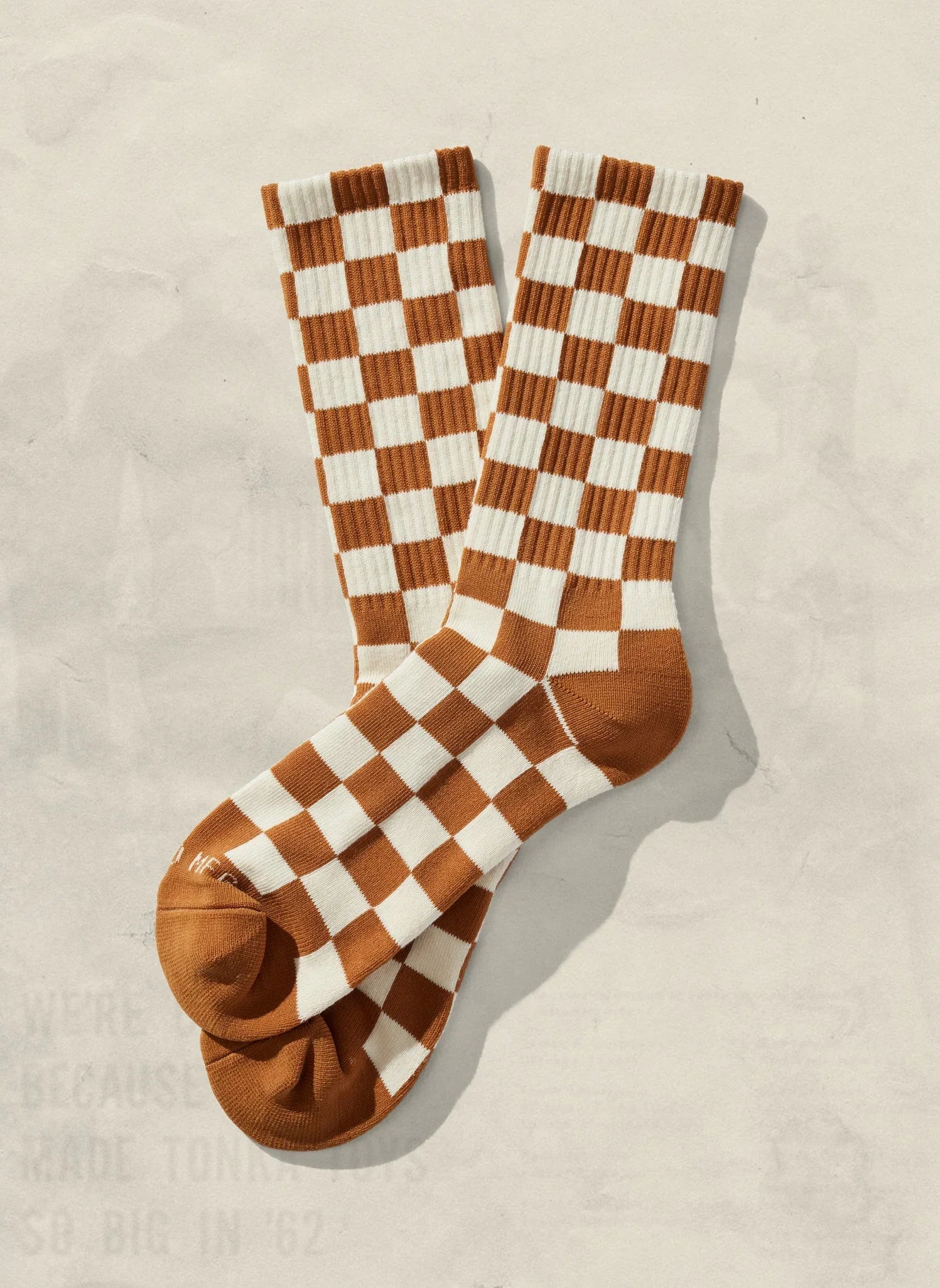Brown and white checkerboard socks on a neutral background, Qu!rk Boutique gift shop
