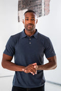 Man modeling a heather navy short sleeve polo shirt, modern urban setting, Qu!rk Boutique