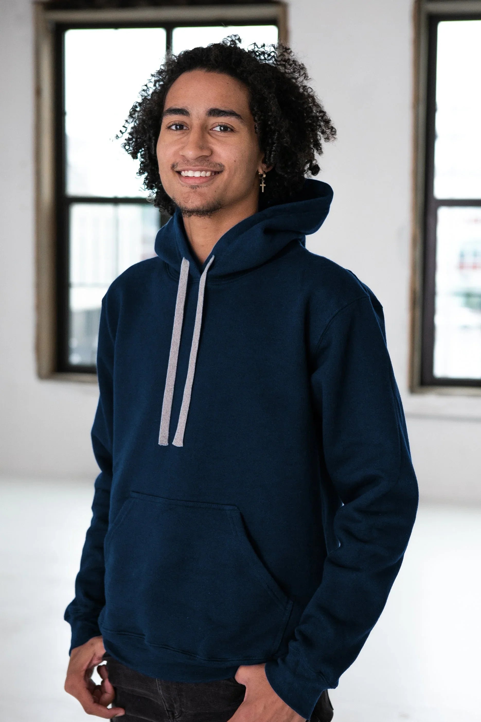 Person in a navy blue hoodie with gray drawstrings, indoors at Qu!rk Boutique.