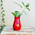 Red ceramic vase with heart design and greenery, displayed on rustic wood at Qu!rk Boutique