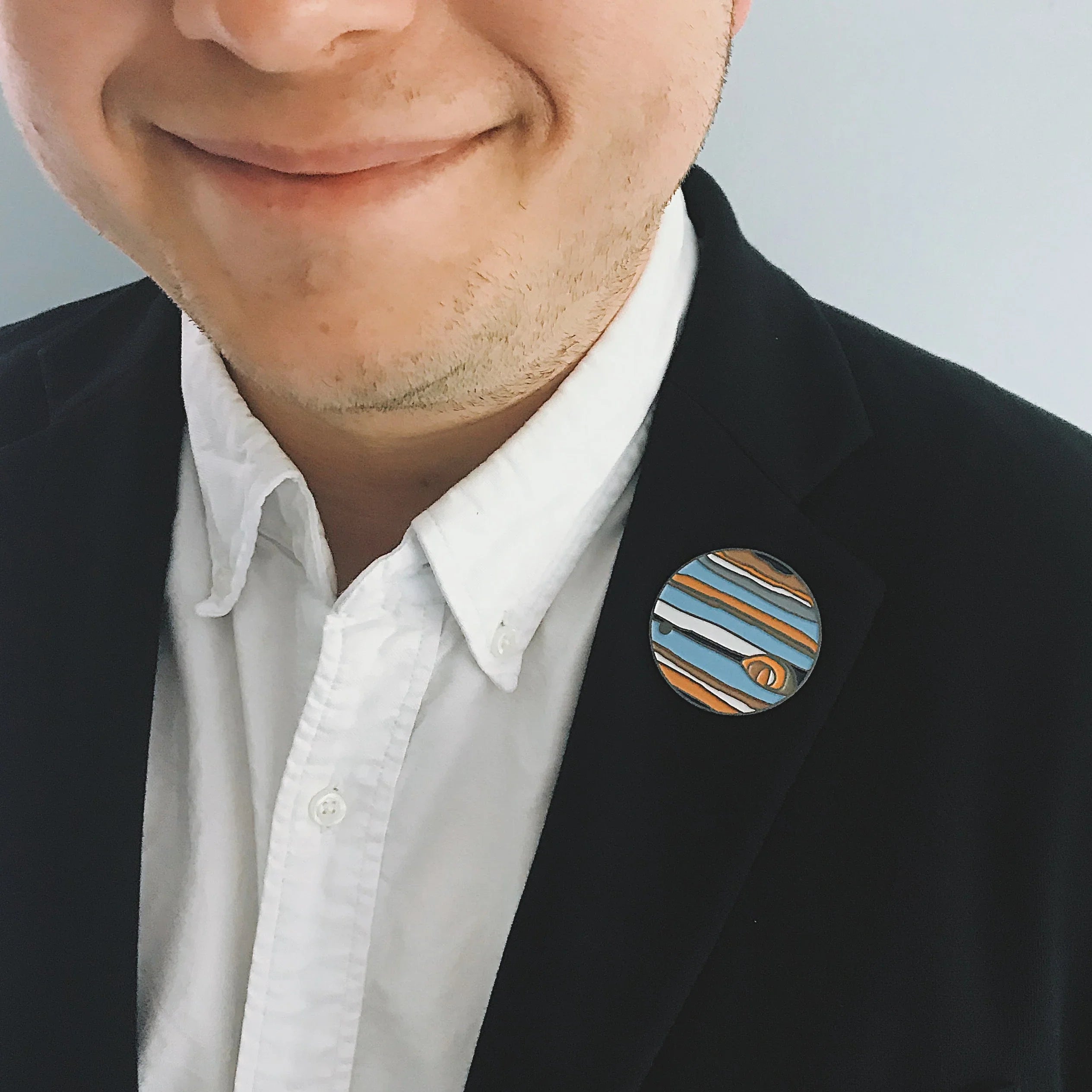 Person in blazer and white shirt wearing artist-designed striped pin from Qu!rk Boutique