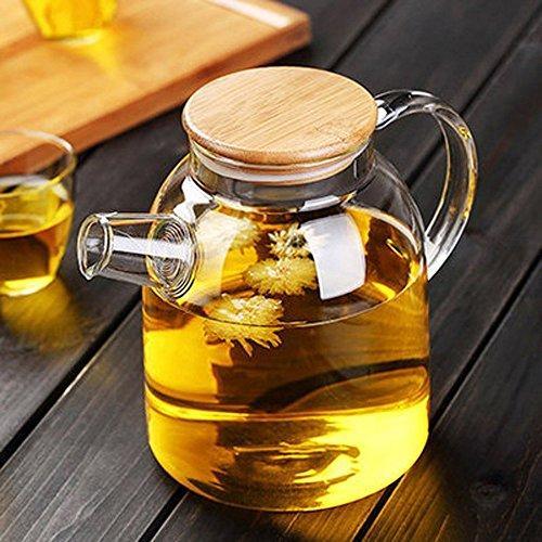 Glass teapot with bamboo lid steeping herbal tea, on dark wood table at Qu!rk Boutique