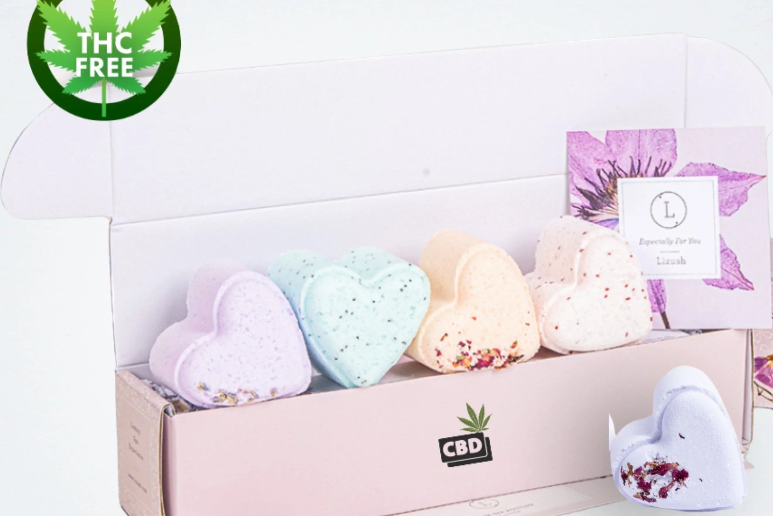 Box of colorful heart-shaped CBD bath bombs with floral accents, THC free label, and gift card
