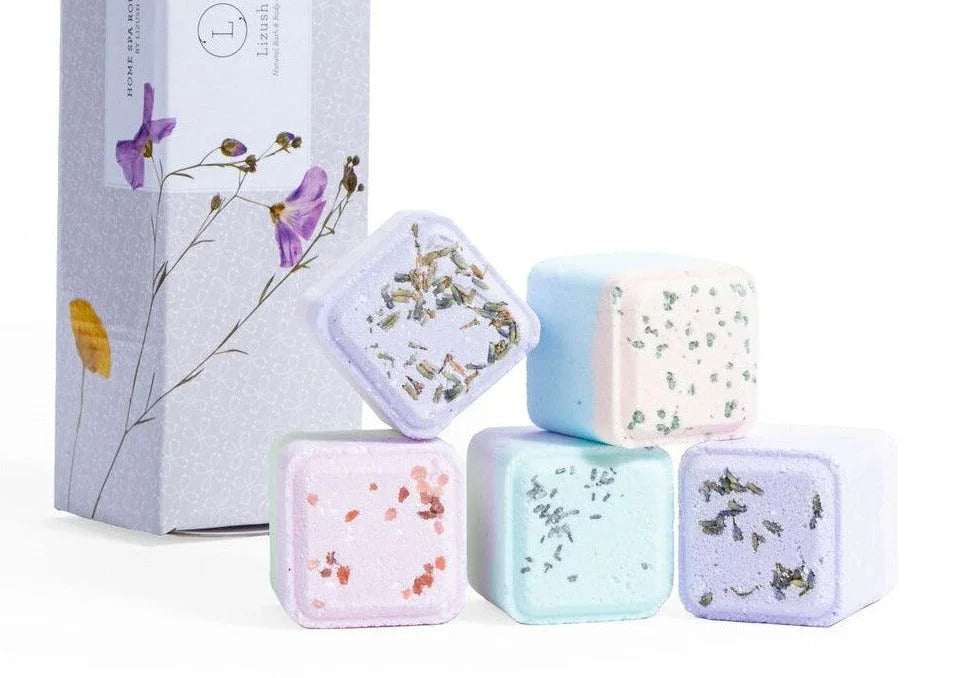 Colorful square shower steamers with dried herbs next to a floral printed box