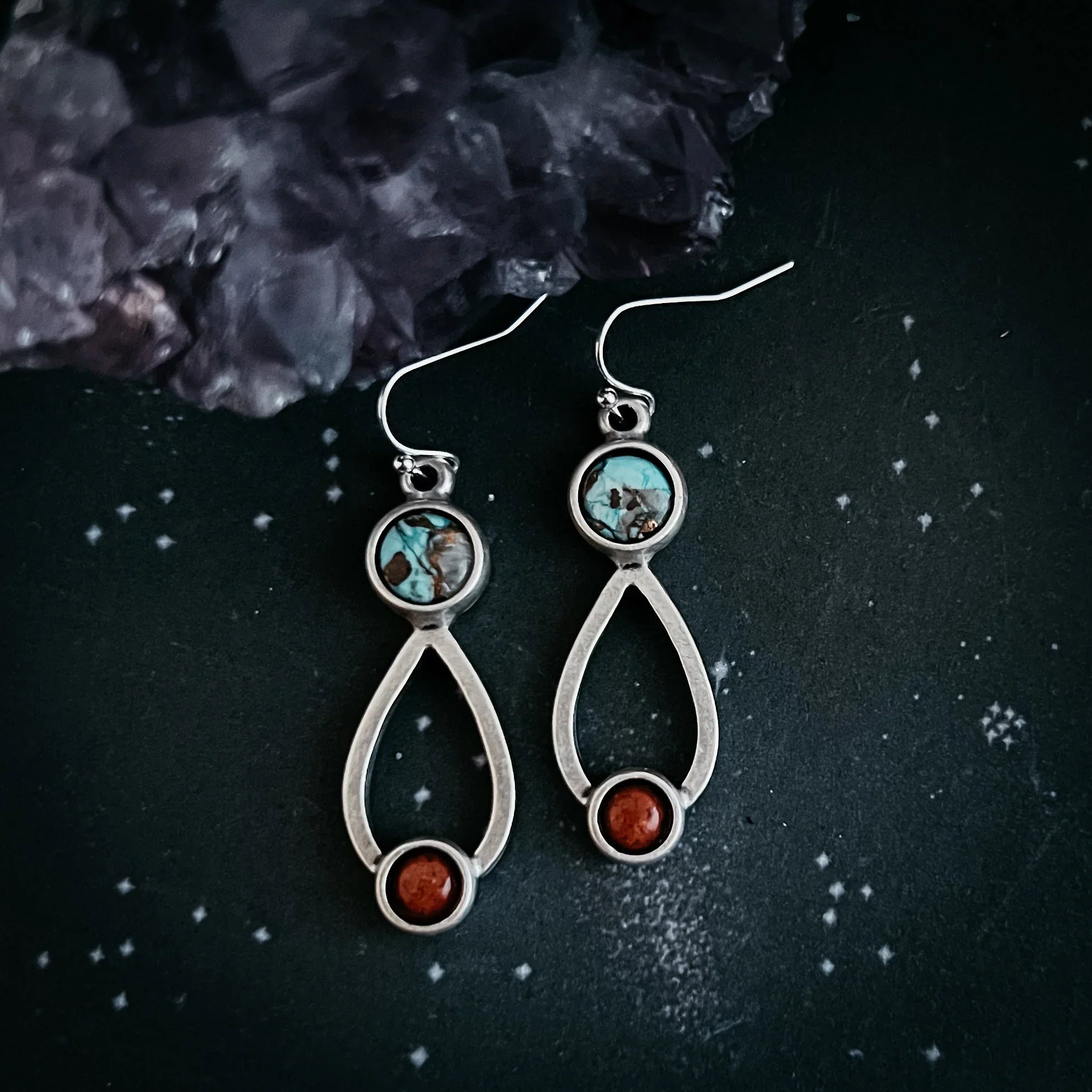 Silver dangle earrings with turquoise and red jasper stones on black star-patterned background