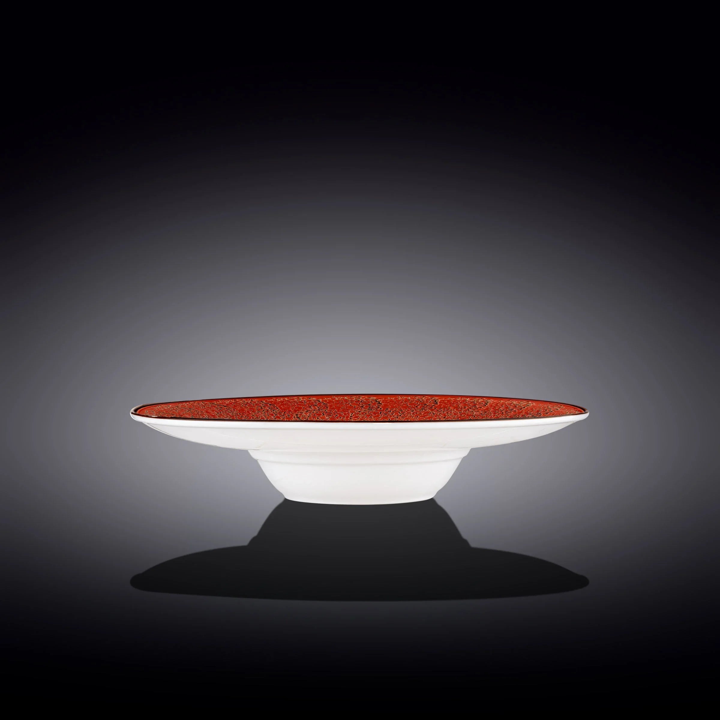 White ceramic bowl with a wide, flat rim and intricate red interior, set against a dark background