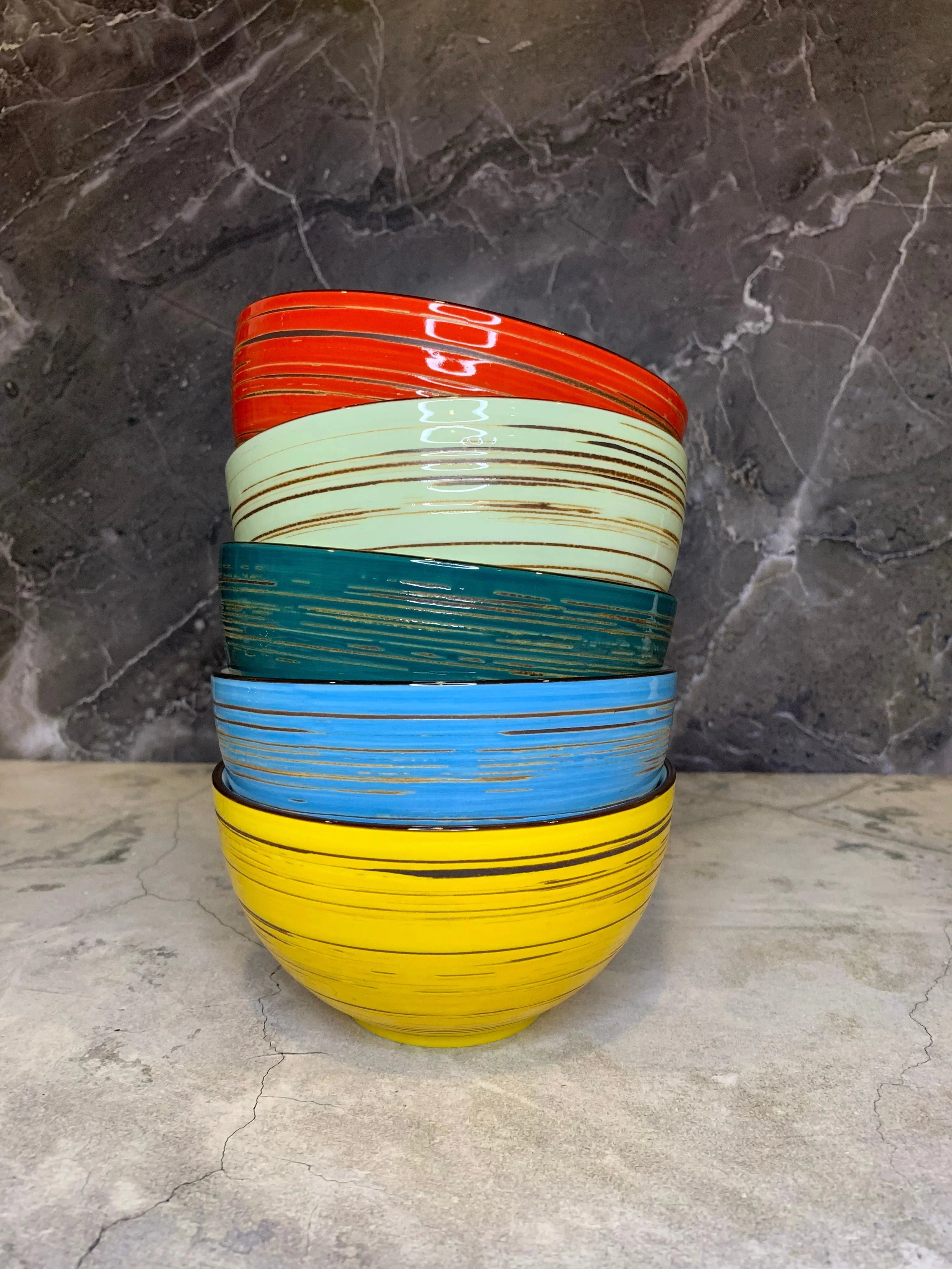 Stack of colorful striped ceramic bowls on marble countertop, artisan home decor at Qu!rk Boutique