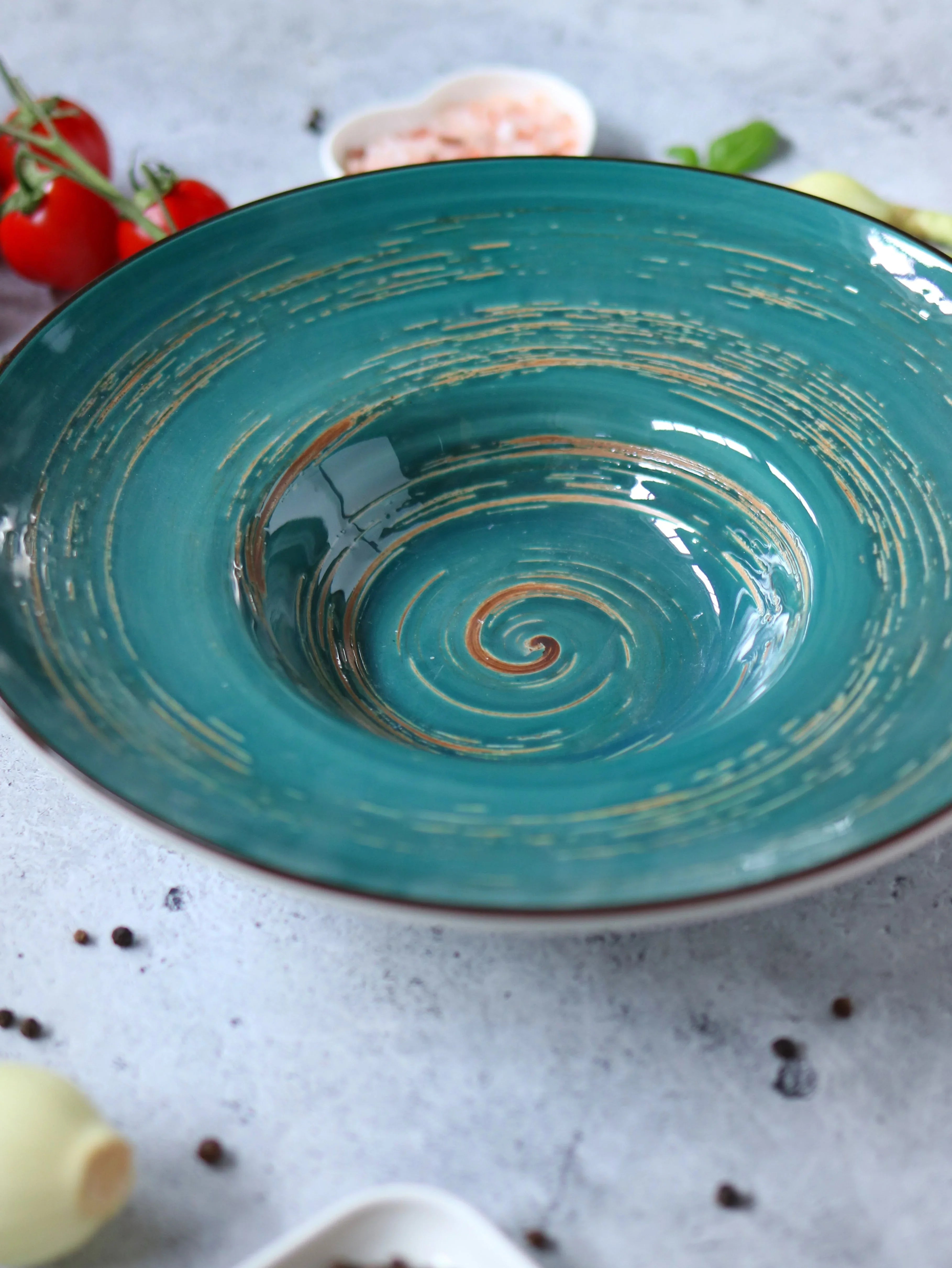 Turquoise swirl ceramic bowl on textured surface with tomatoes and spices, Qu!rk Boutique