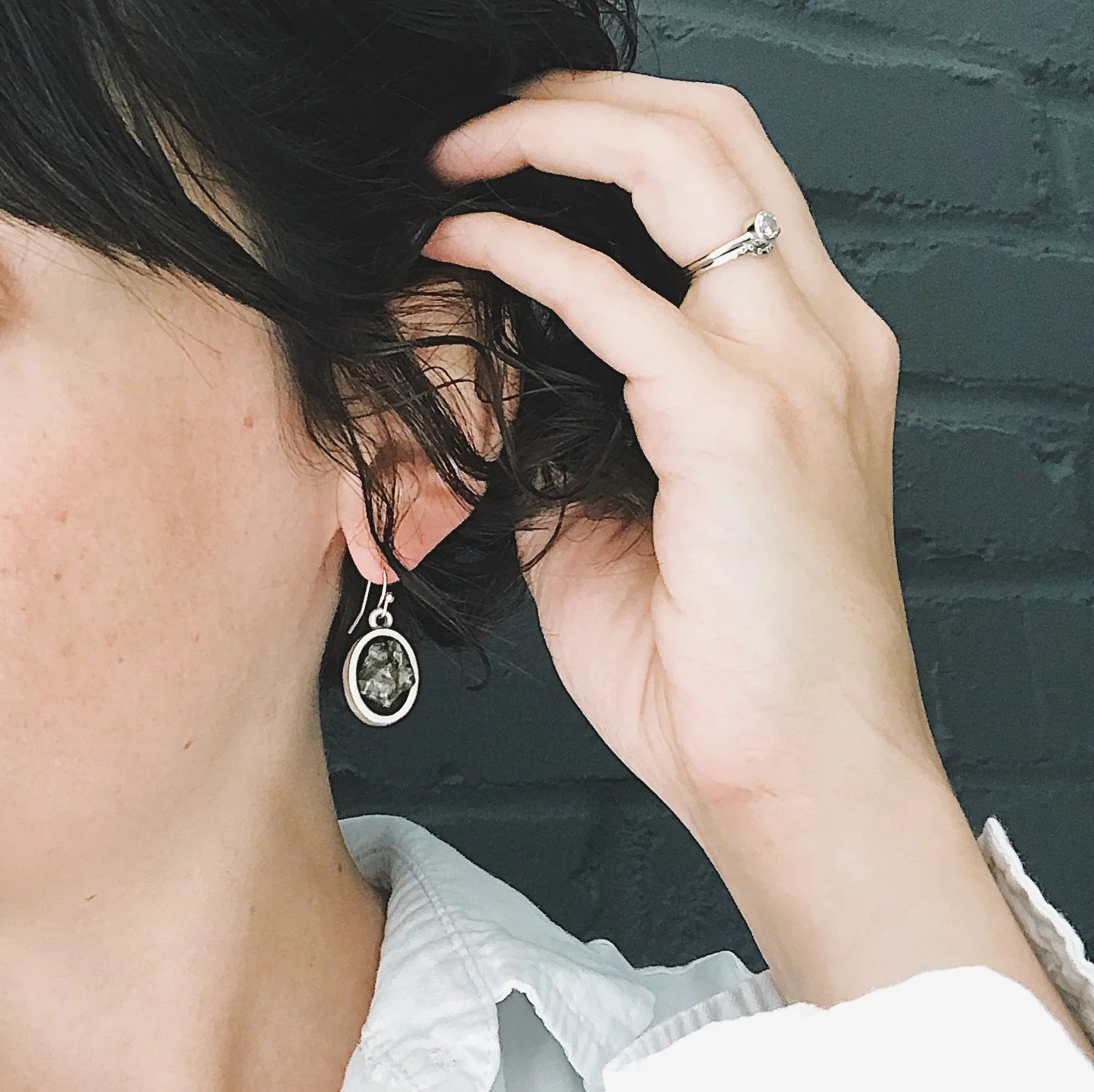 Woman wearing silver gemstone dangle earring and ring, Qu!rk Boutique jewelry close-up