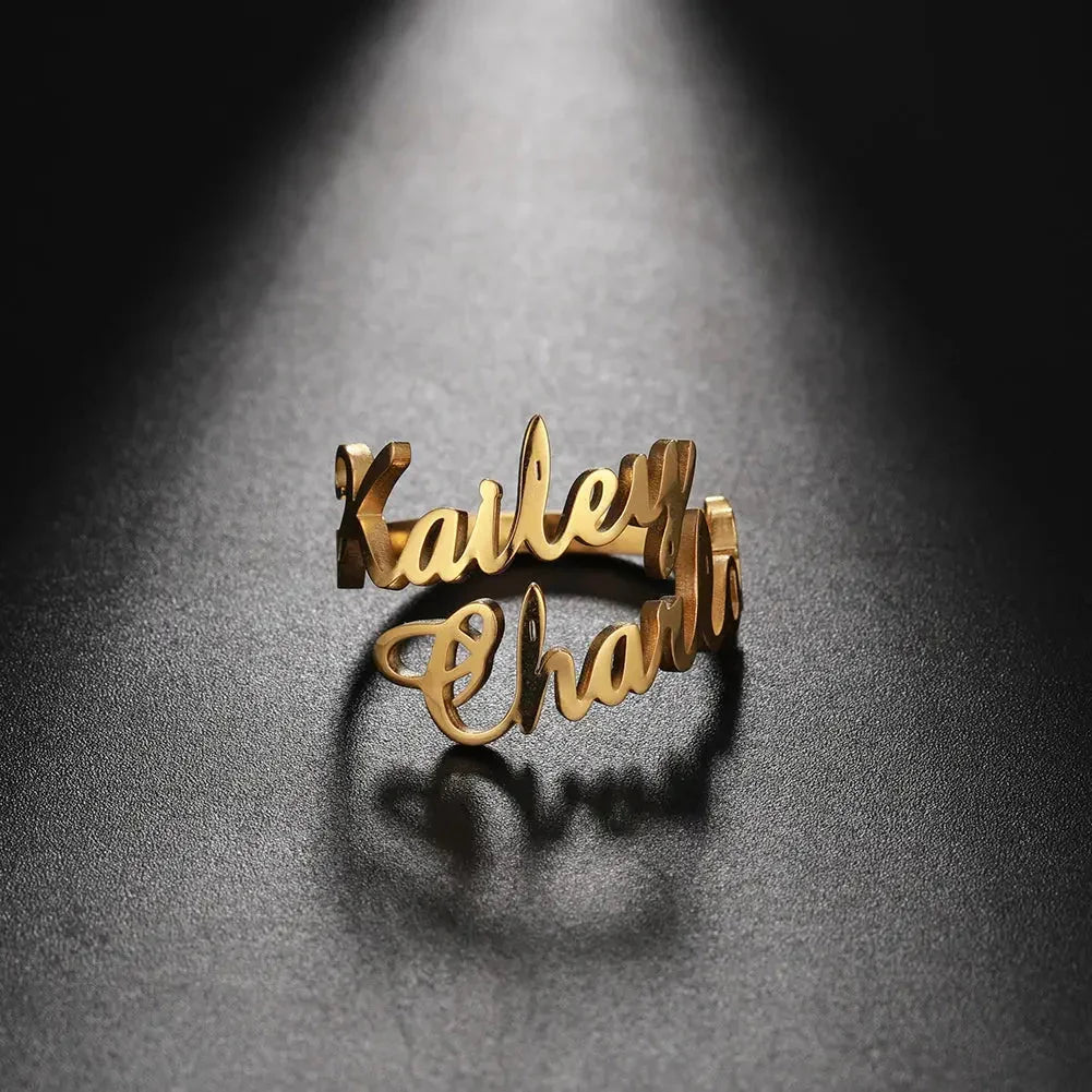 Gold custom name ring with names Kailey and Charlie illuminated on black textured surface