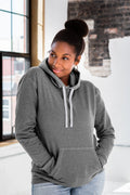 Woman in grey hoodie with front pocket from Qu!rk Boutique, standing in loft setting