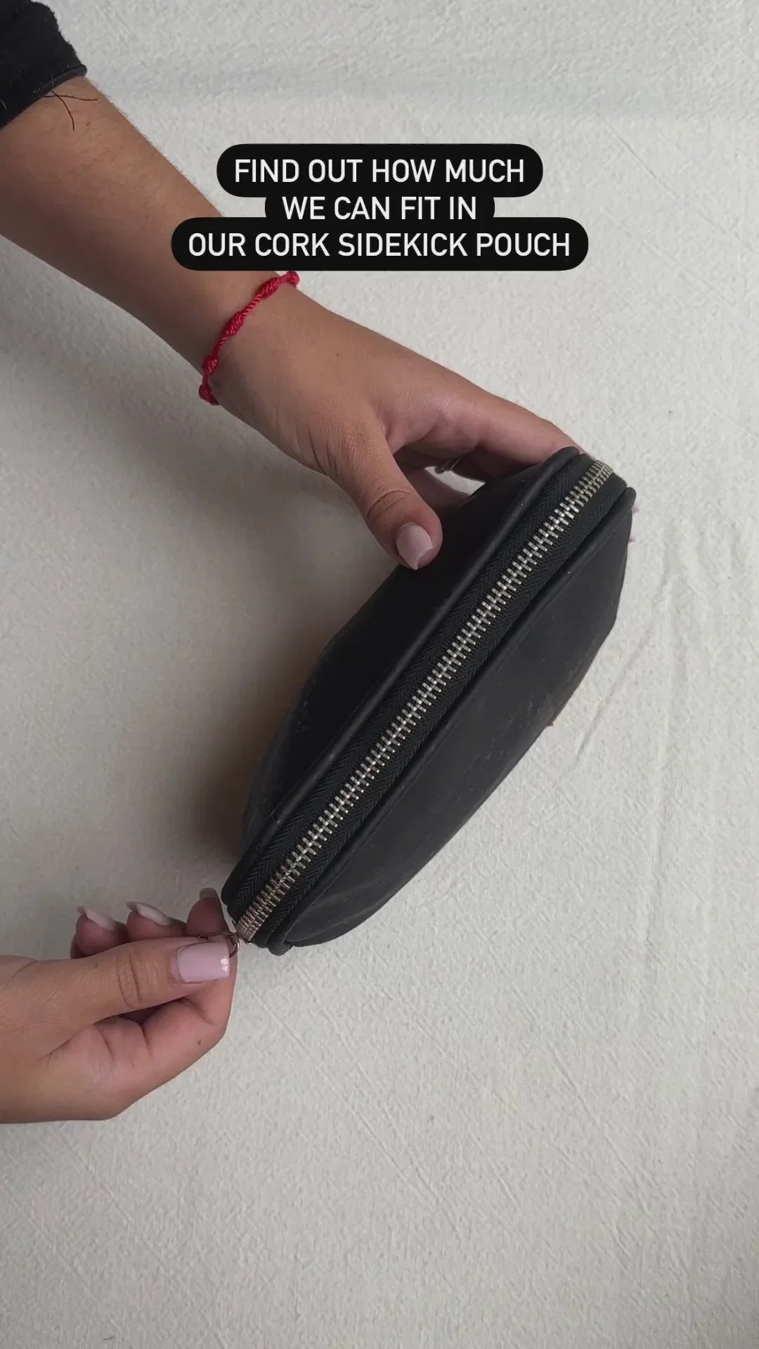 Hands holding black cork sidekick pouch with zipper, Qu!rk Boutique eco-friendly accessory