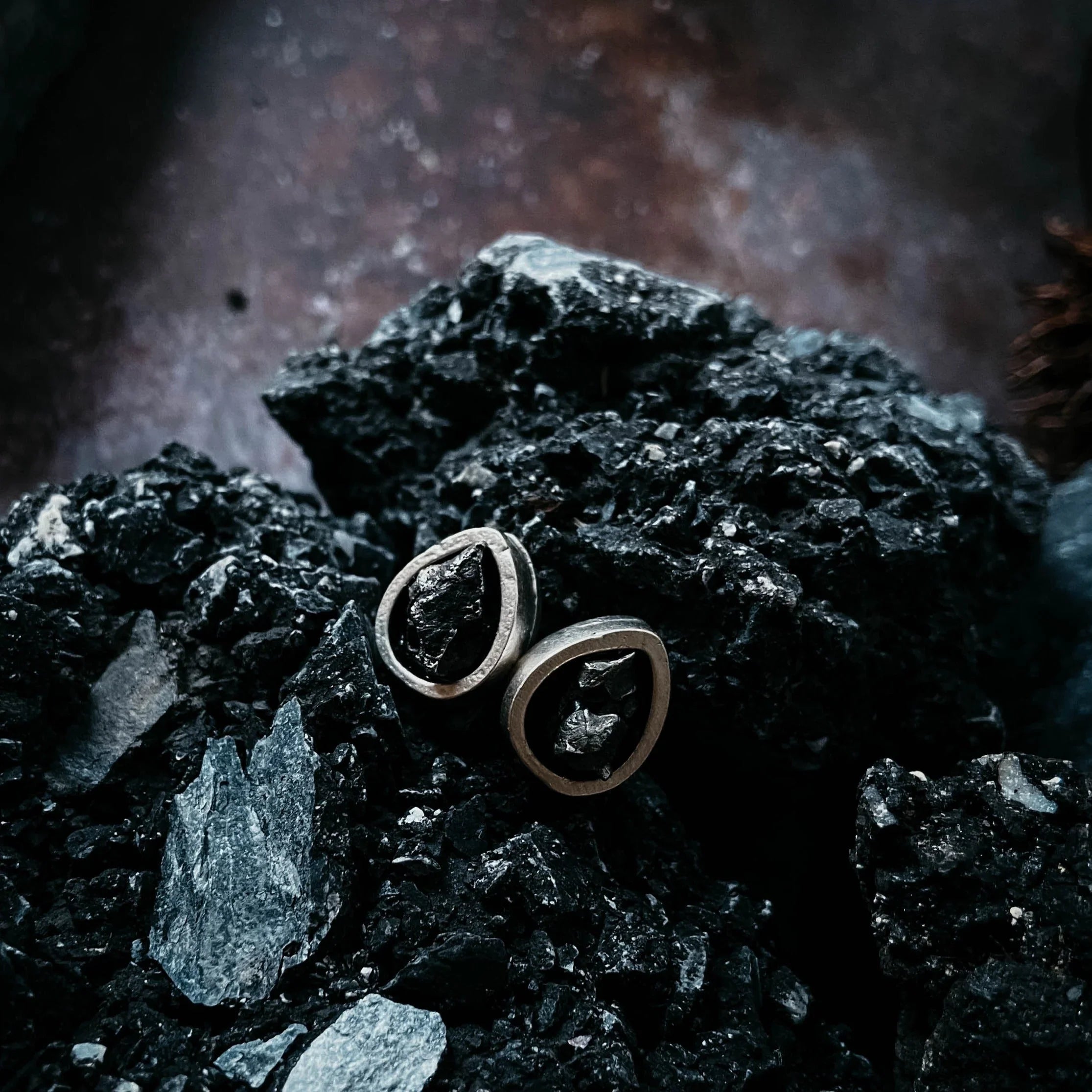 Recycled metal earrings with raw black stones on textured black rocks at Qu!rk Boutique