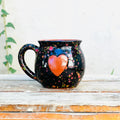 Handmade black mug with colorful splatter pattern and raised red heart, Qu!rk Boutique