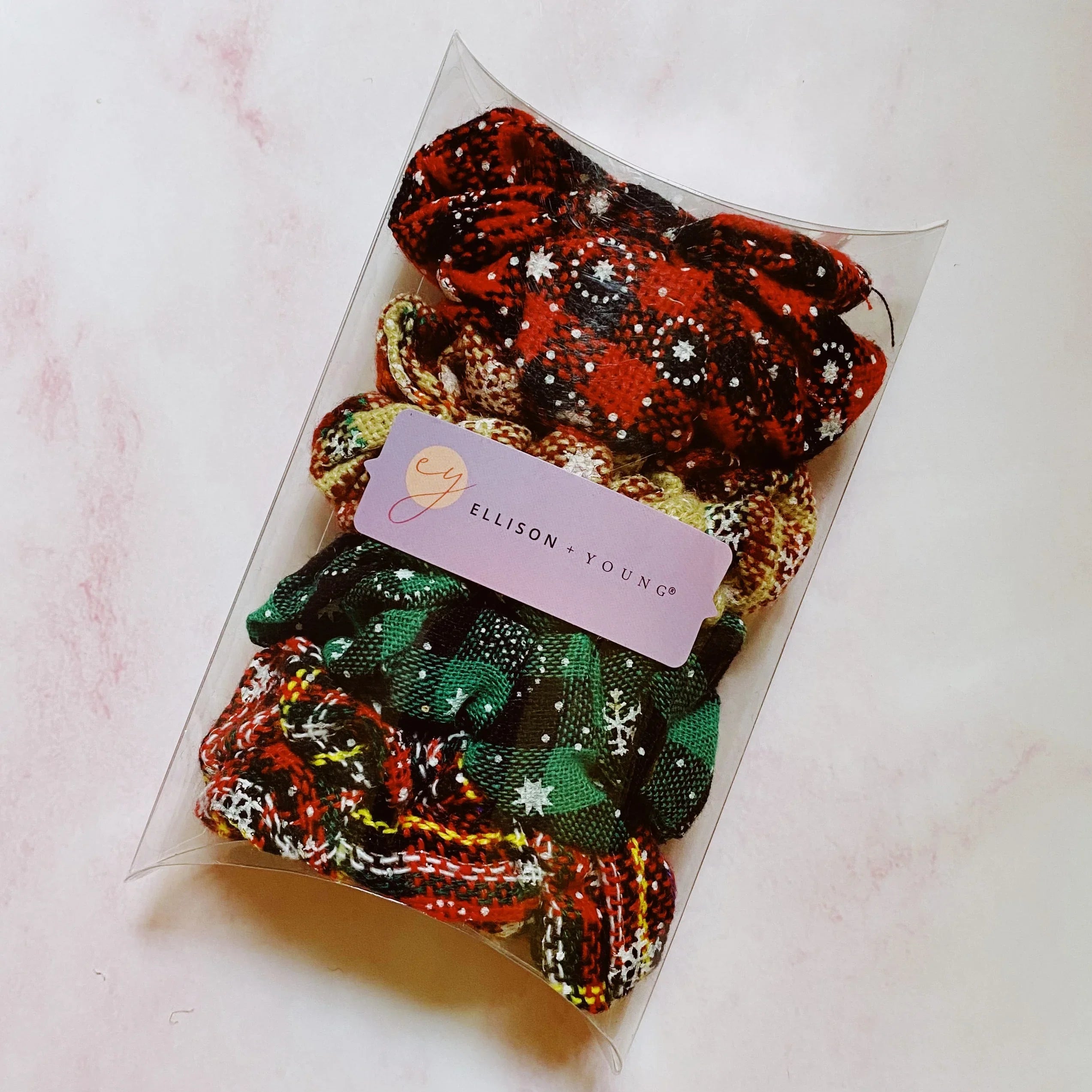 Set of four patterned fabric scrunchies in a clear packaging with Ellison + Young label