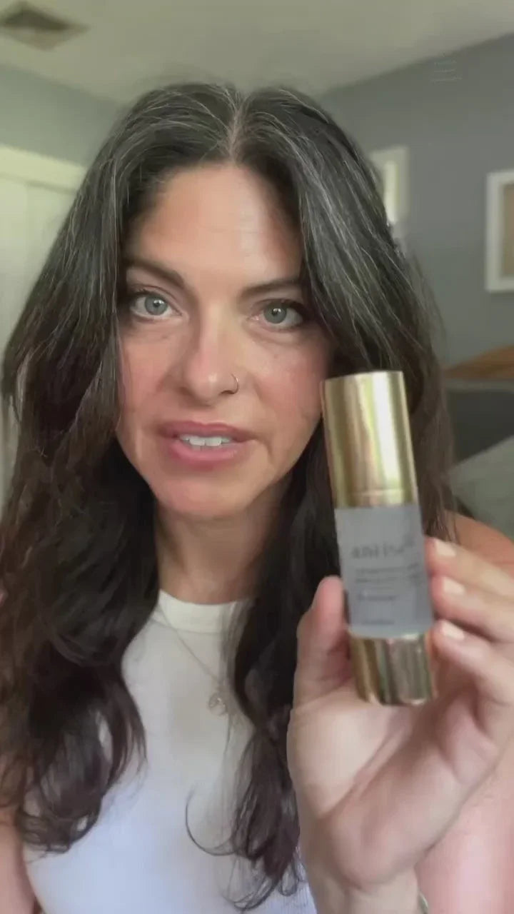 Woman with long dark hair holding gold-capped beauty product, Qu!rk Boutique gift shop style.