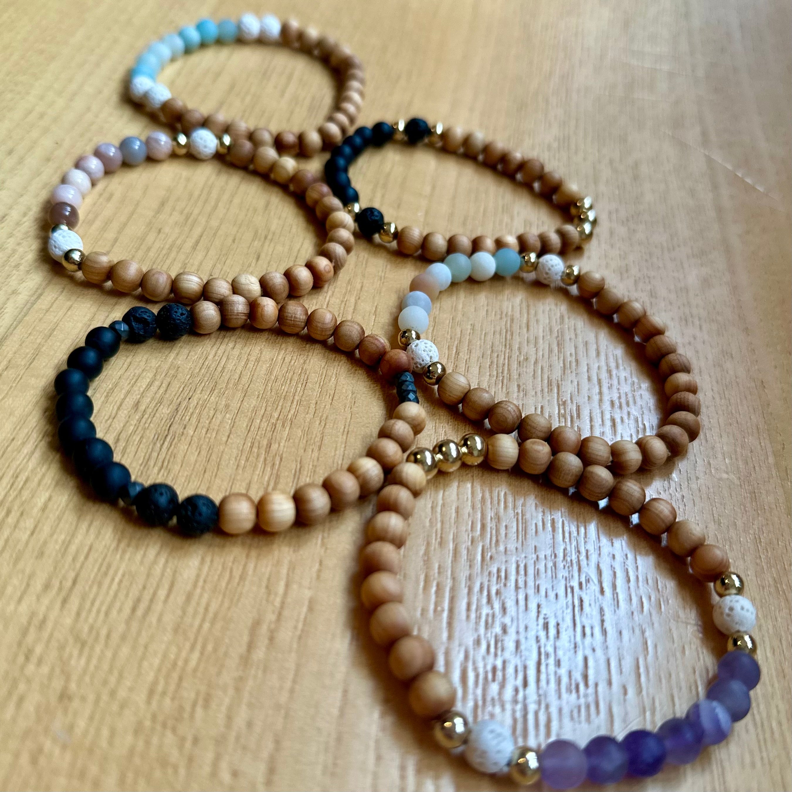 Beaded wooden bracelets with natural and colorful stone accents on wooden surface
