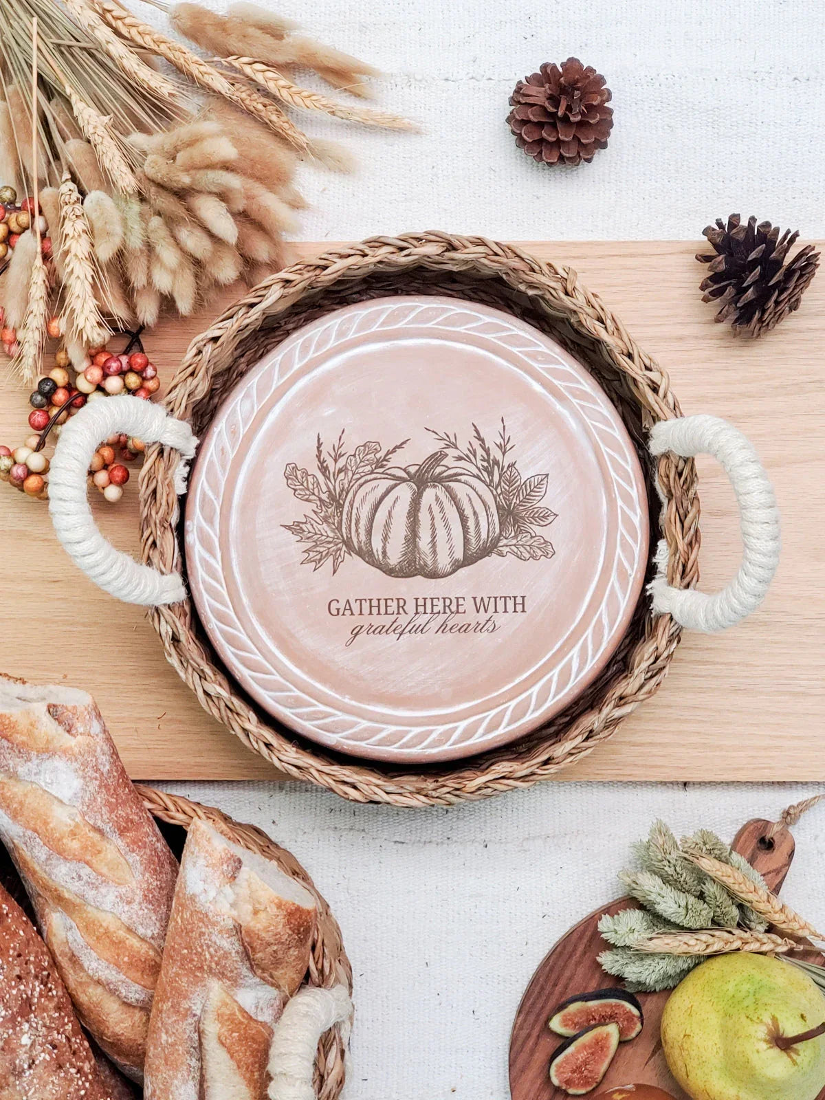 Rustic autumn decor with woven tray, pumpkin design plate, pinecones, bread, and fall foliage