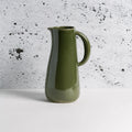 Olive green ceramic pitcher with handle on white table, minimalist modern decor at Qu!rk Boutique