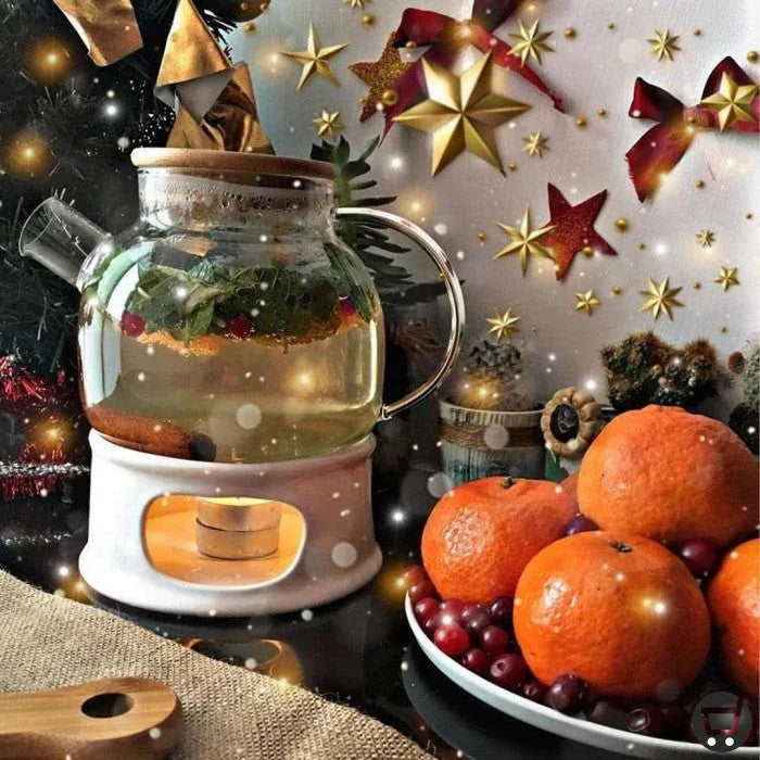 Festive glass teapot with herbs and citrus on warmer, tangerines and cranberries, holiday decor.