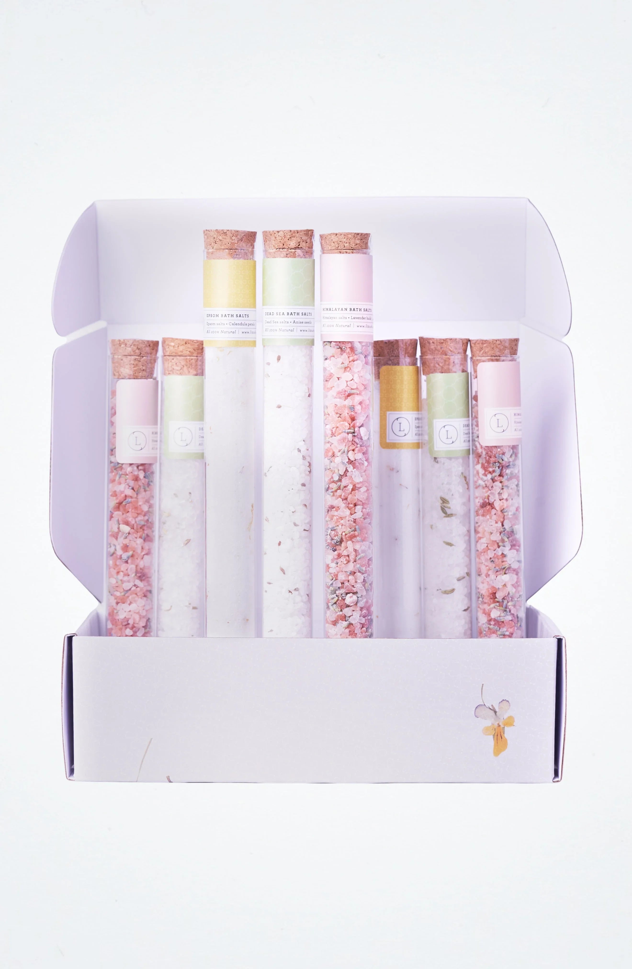 Open box with eight corked glass tubes of colorful bath salts in pastel labels