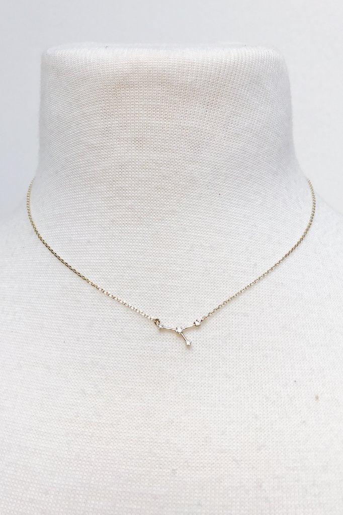 Delicate gold necklace with a small constellation pendant displayed on a white fabric bust