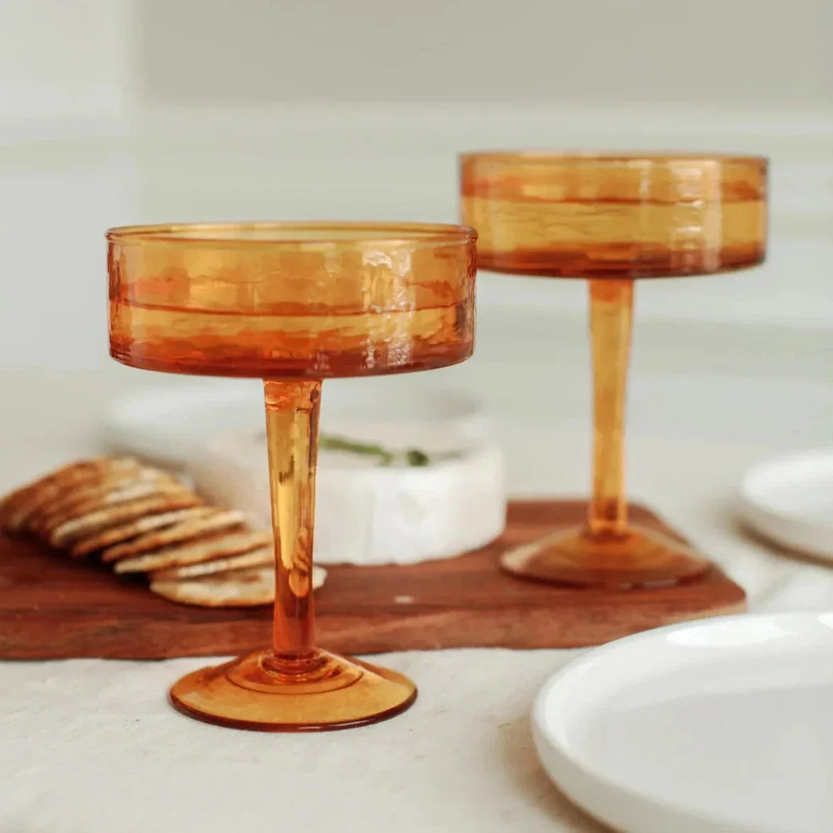 Amber glass coupe glasses on a cheese board with crackers, styled for Qu!rk Boutique