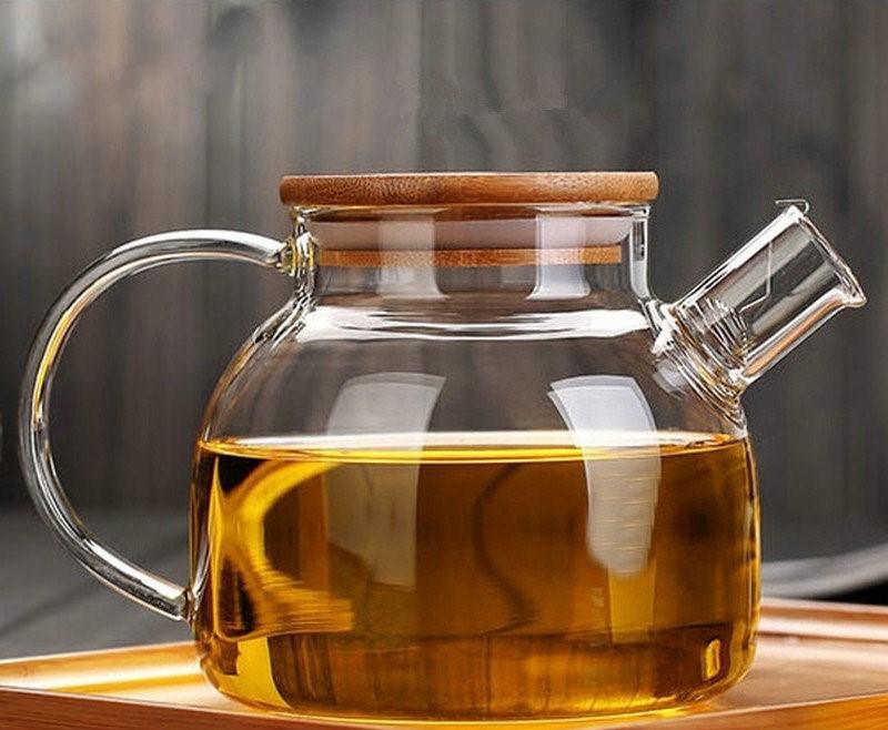 Clear glass teapot with wooden lid, filled with tea, on a wooden tray, Qu!rk Boutique style