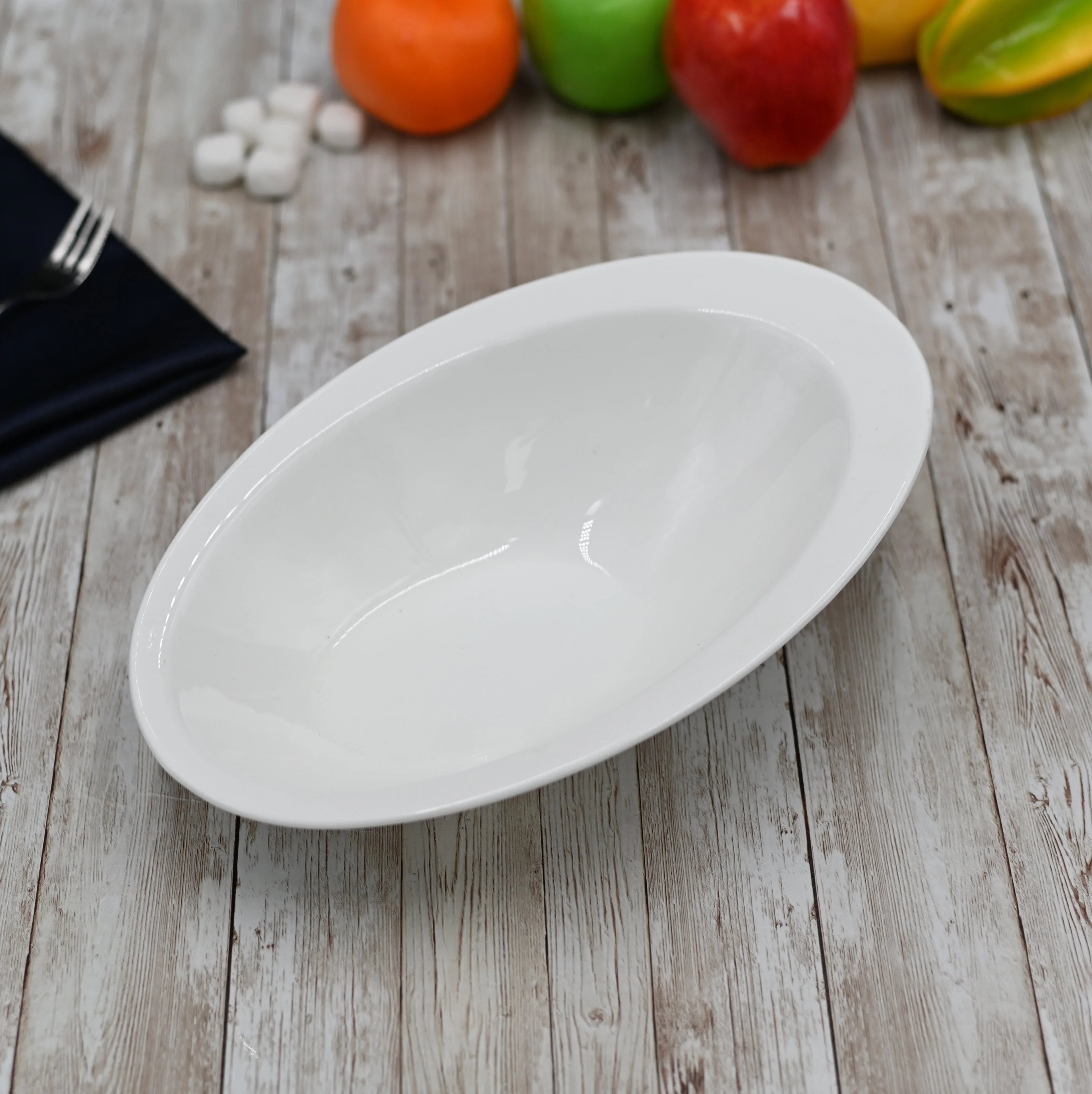 White oval ceramic serving bowl on rustic wood table with colorful fruit, Qu!rk Boutique