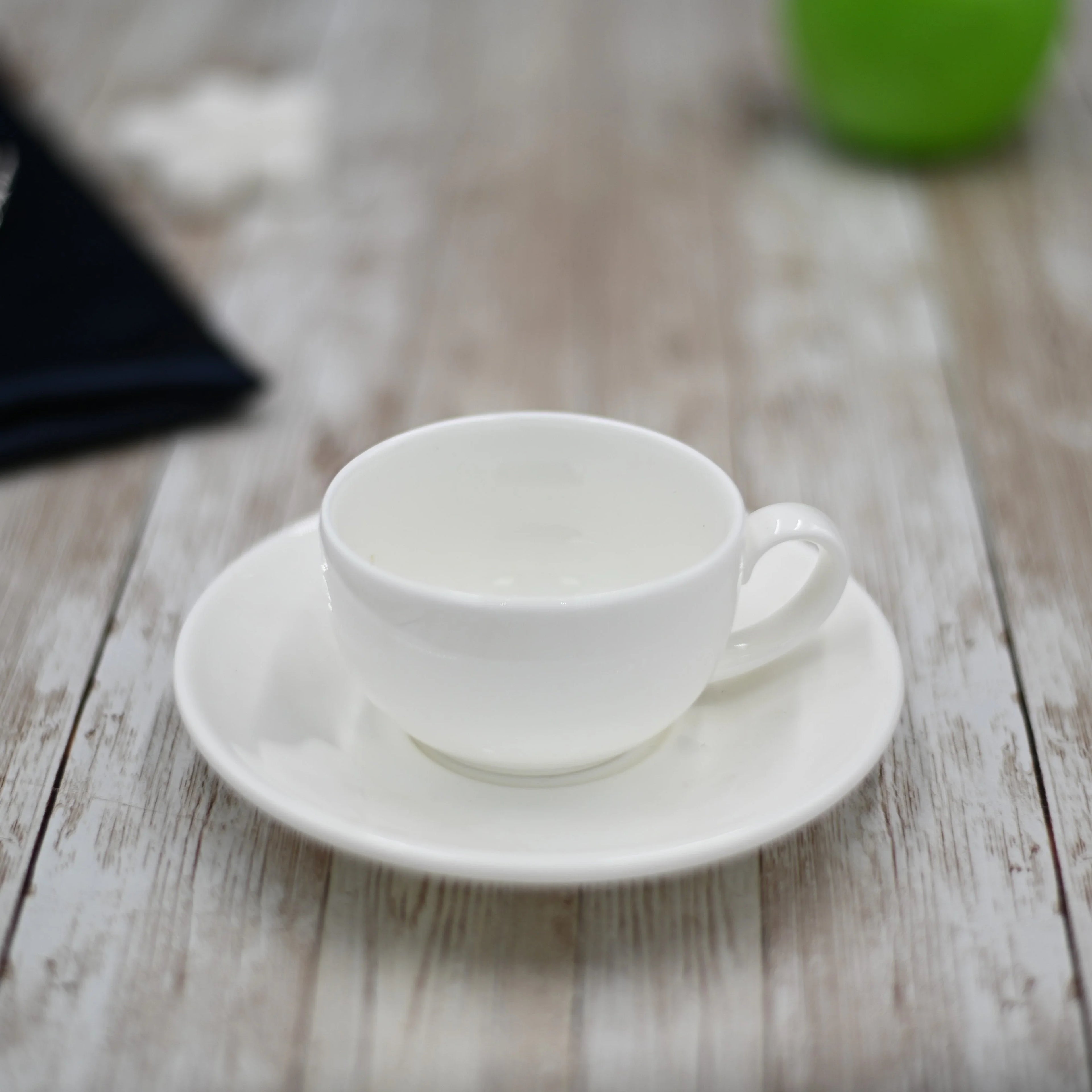 White ceramic teacup and saucer on rustic wood table at Qu!rk Boutique gift shop