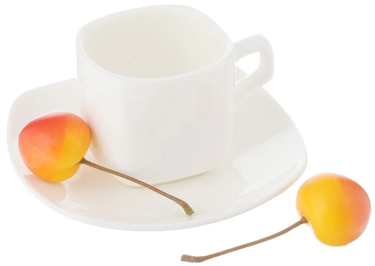 Modern white square teacup and saucer with two yellow-red cherries on a white background
