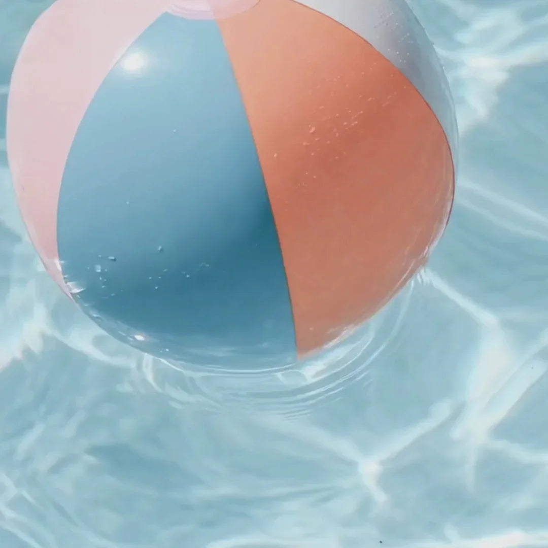 Colorful pastel beach ball floating in clear blue pool water at Qu!rk Boutique