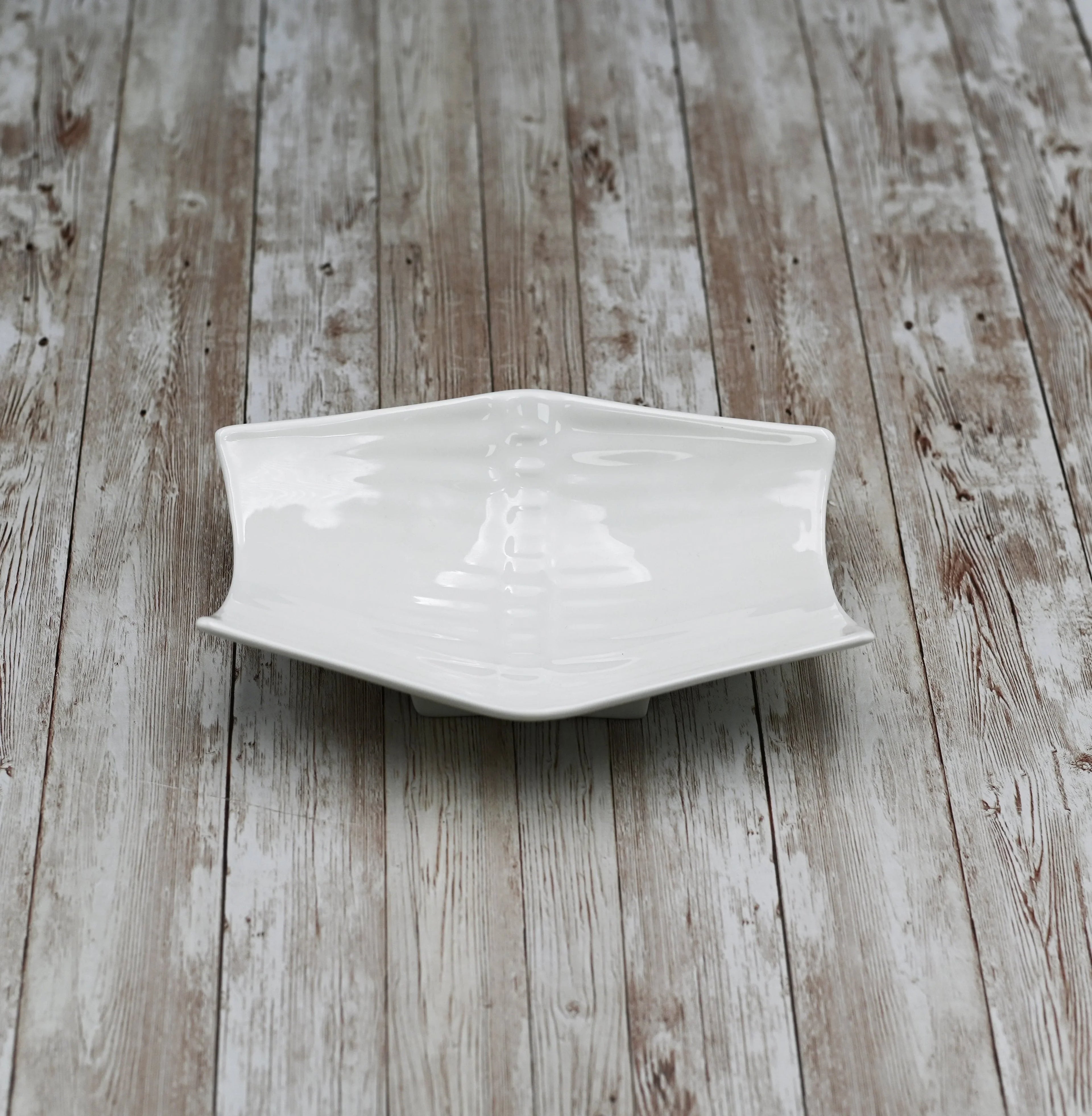 White ceramic hexagon plate on rustic wood background, Qu!rk Boutique artist-designed home decor