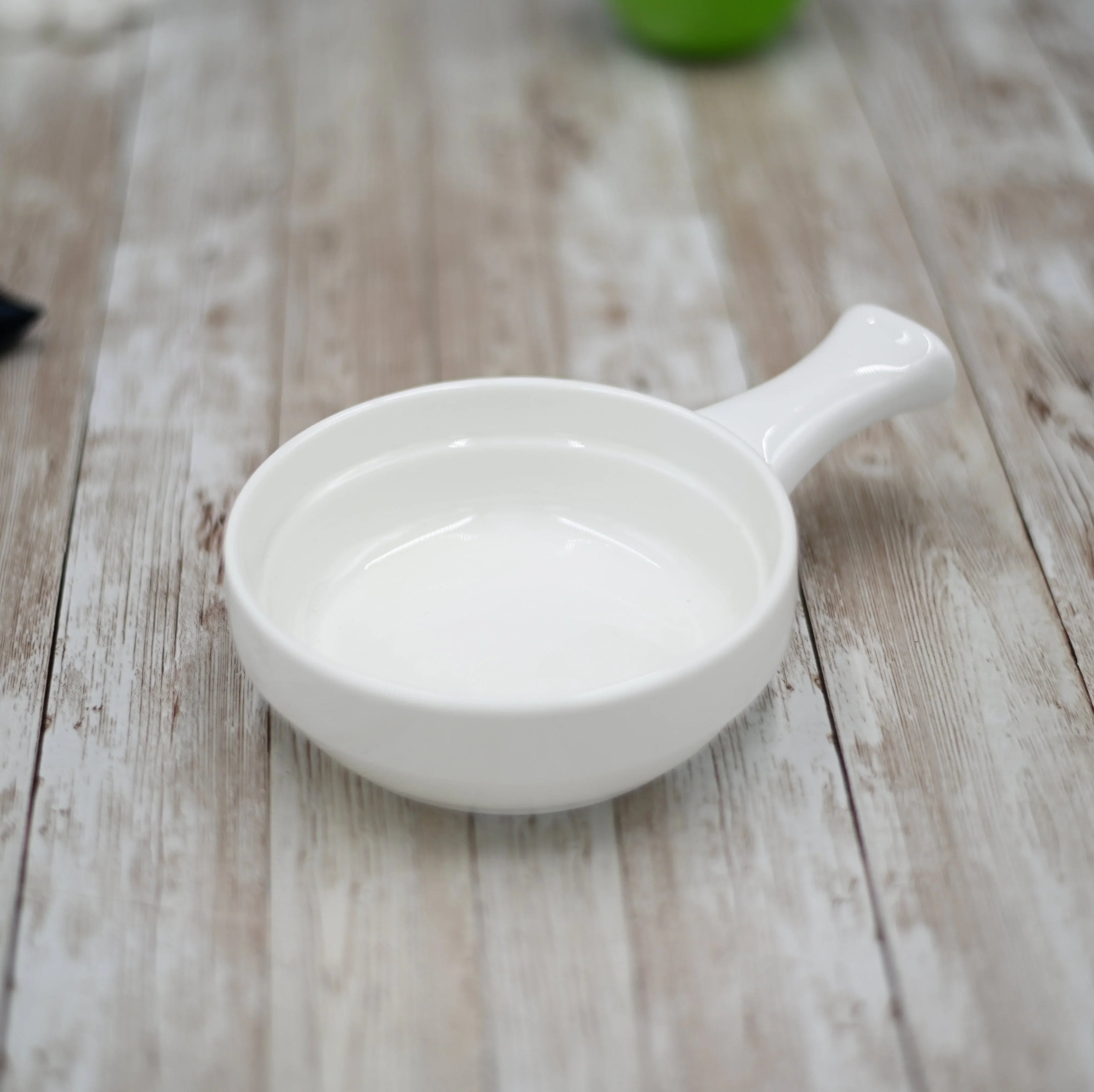 White ceramic dish with handle on rustic wood surface, Qu!rk Boutique tableware