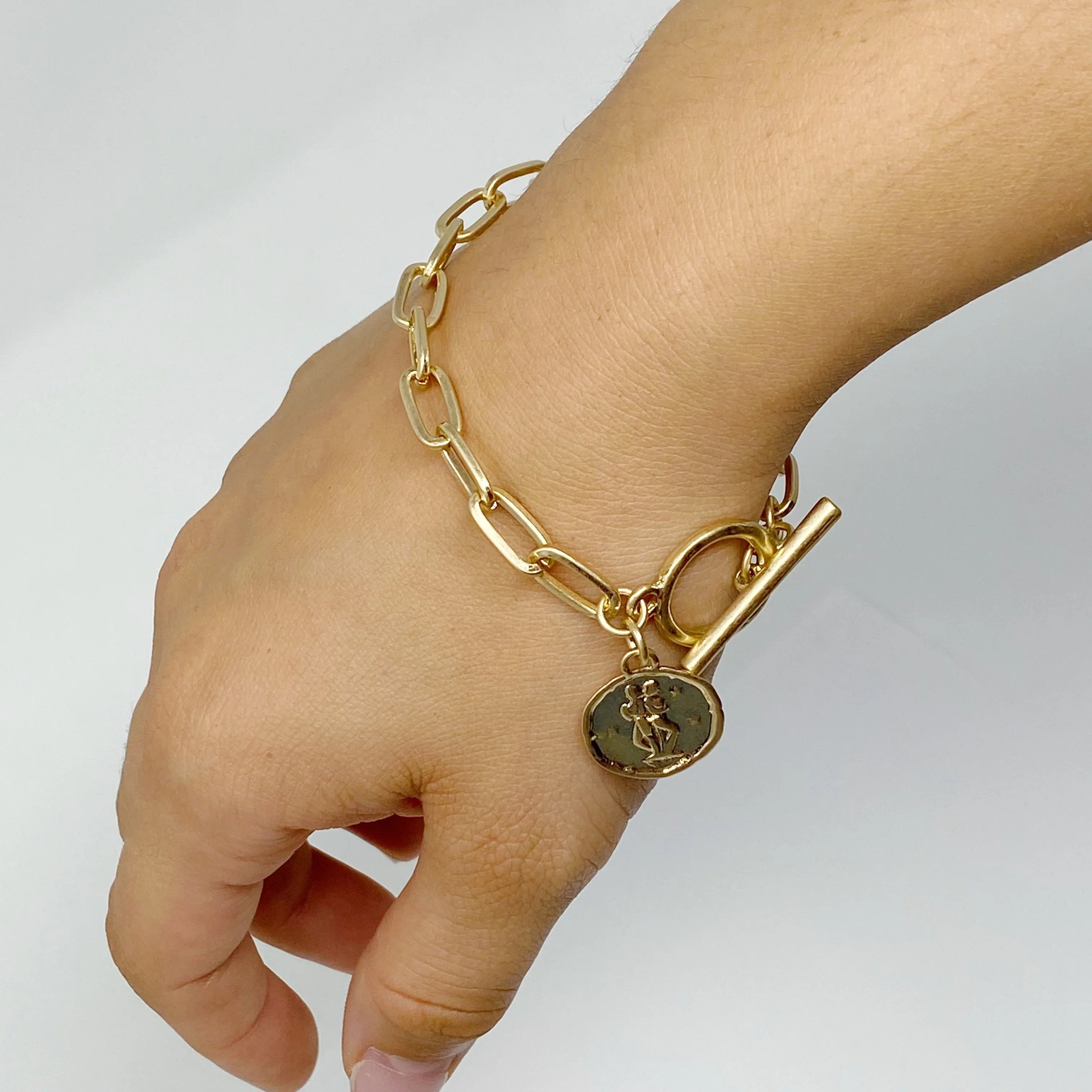 Gold chain link bracelet with toggle clasp and engraved charm on wrist