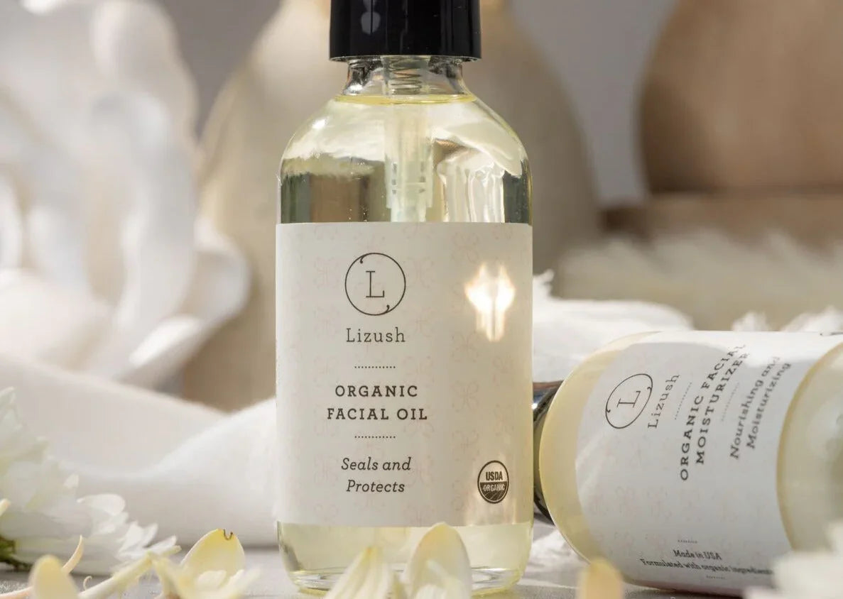 Lizush organic facial oil bottle with dropper on soft neutral background, surrounded by flower petals