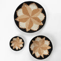 Set of three woven bowls with geometric tan, cream, and black star patterns on white background