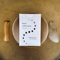 Lunar Reflections box by Slow North with moon phases design on a round cushion, earth-toned background