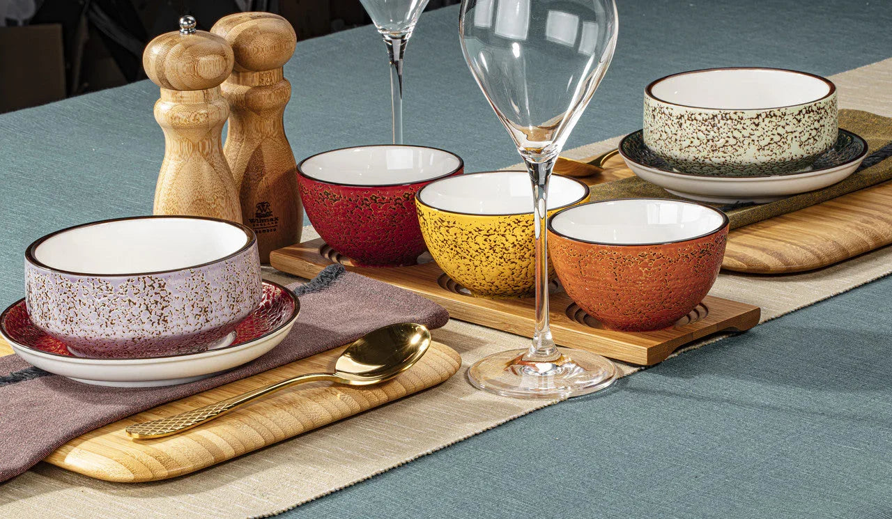 Colorful speckled soup bowls and cups on wooden boards, set on a stylish table at Qu!rk Boutique.